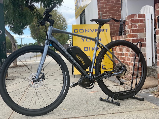 A giant electric motor ebike conversions in gray color with a brand sticker named giant on the frame, equipped with a water bottle cage and a bike stand.